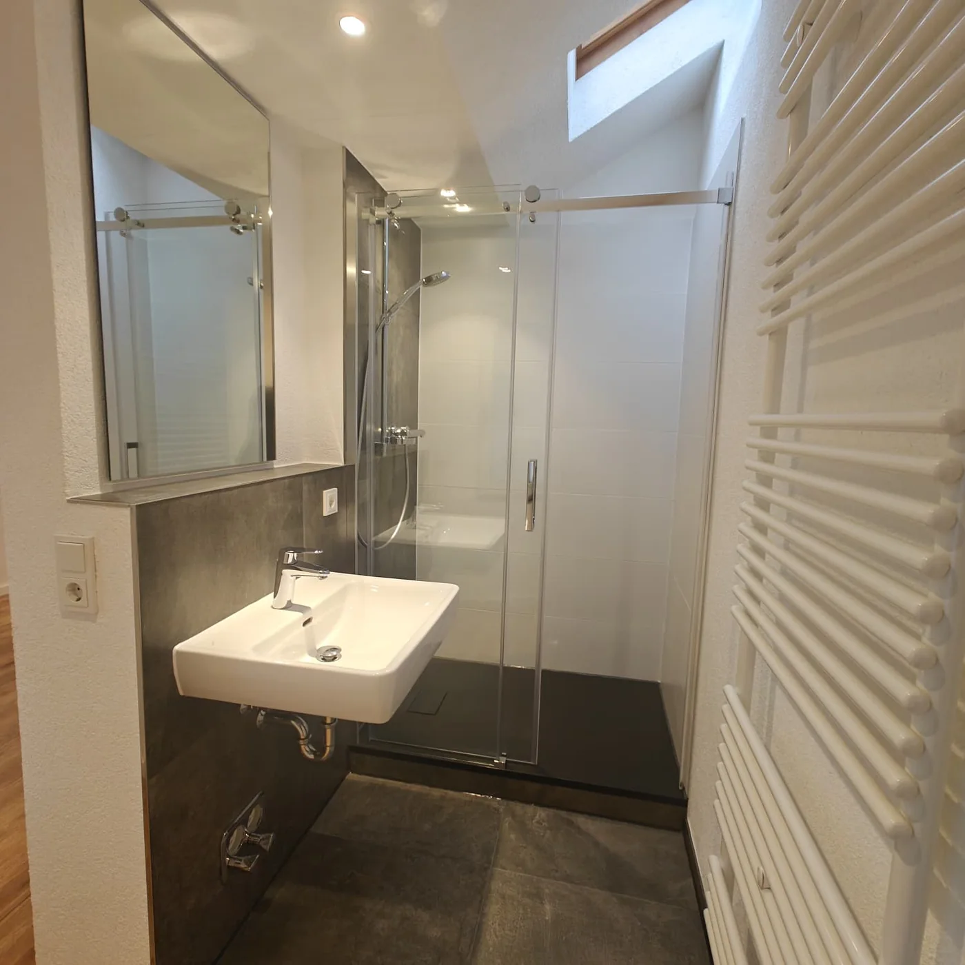 Modernes Duschbad mit bodengleicher Glasdusche, Waschtisch und Handtuchheizkörper
