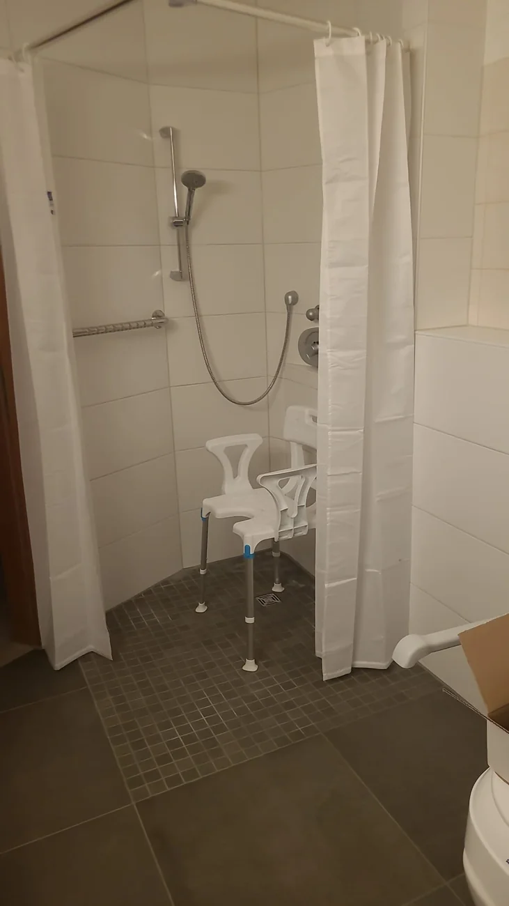Neue bodengleiche Dusche nach dem barrierefreien Badumbau mit Haltegriff und Duschsitz